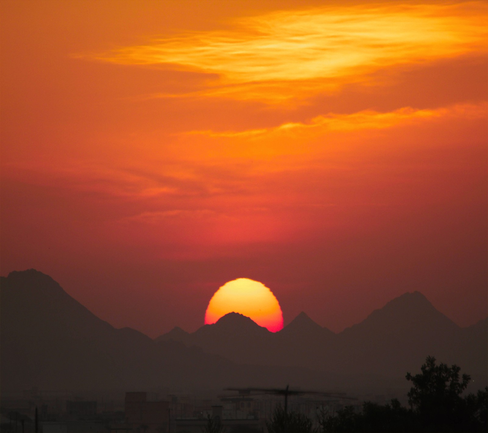 Atardecer sobre una ciudad con montañas al fondo (buenos días, mañana, amanecer)