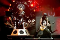 Guns N' Roses electrifying performance at the Not in This Lifetime Tour, featuring Axl Rose on vocals and Slash on guitar amidst a dynamic stage setup.