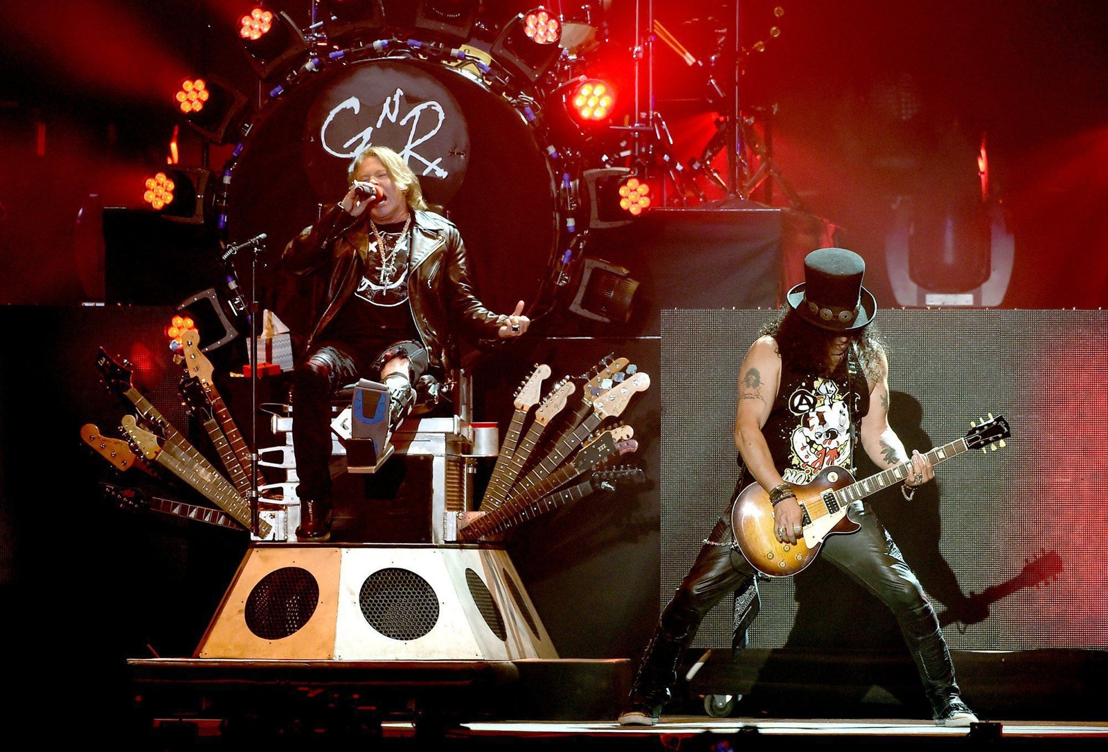 Imagen de un hombre con una guitarra y una mujer con un sombrero en un fondo borroso (guns n roses, no en este tour de vida, not in this lifetime tour, apetito por destrucción, desempeño)