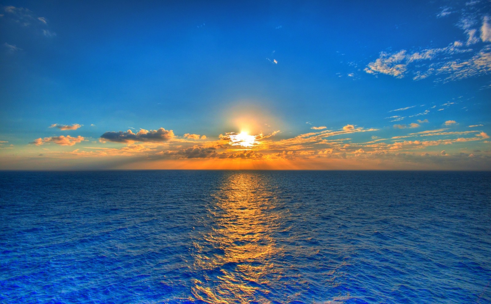 A view of the sun setting over the ocean with clouds (sunrise, sea, horizon, ocean, sunset)