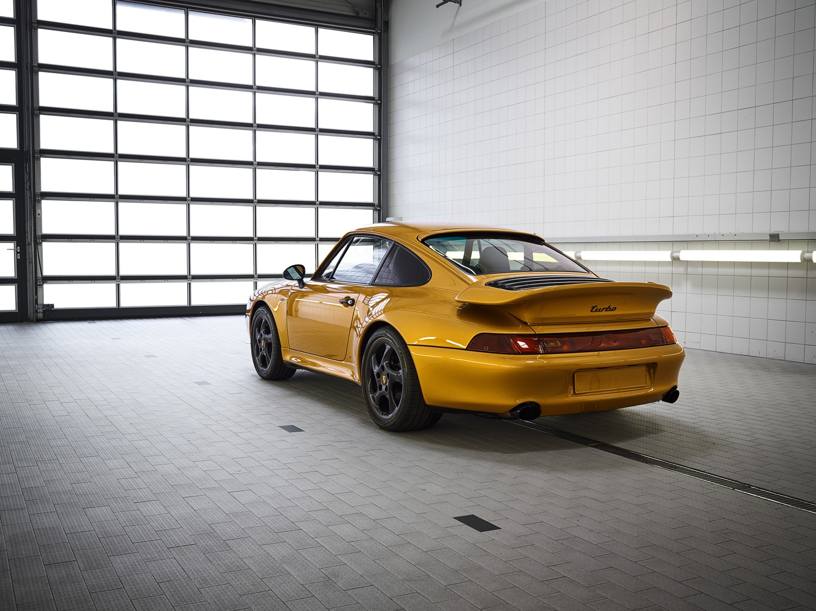 Arafed yellow sports car parked in a large garage (porsche, porsche 911, porsche 930, sports car, car)