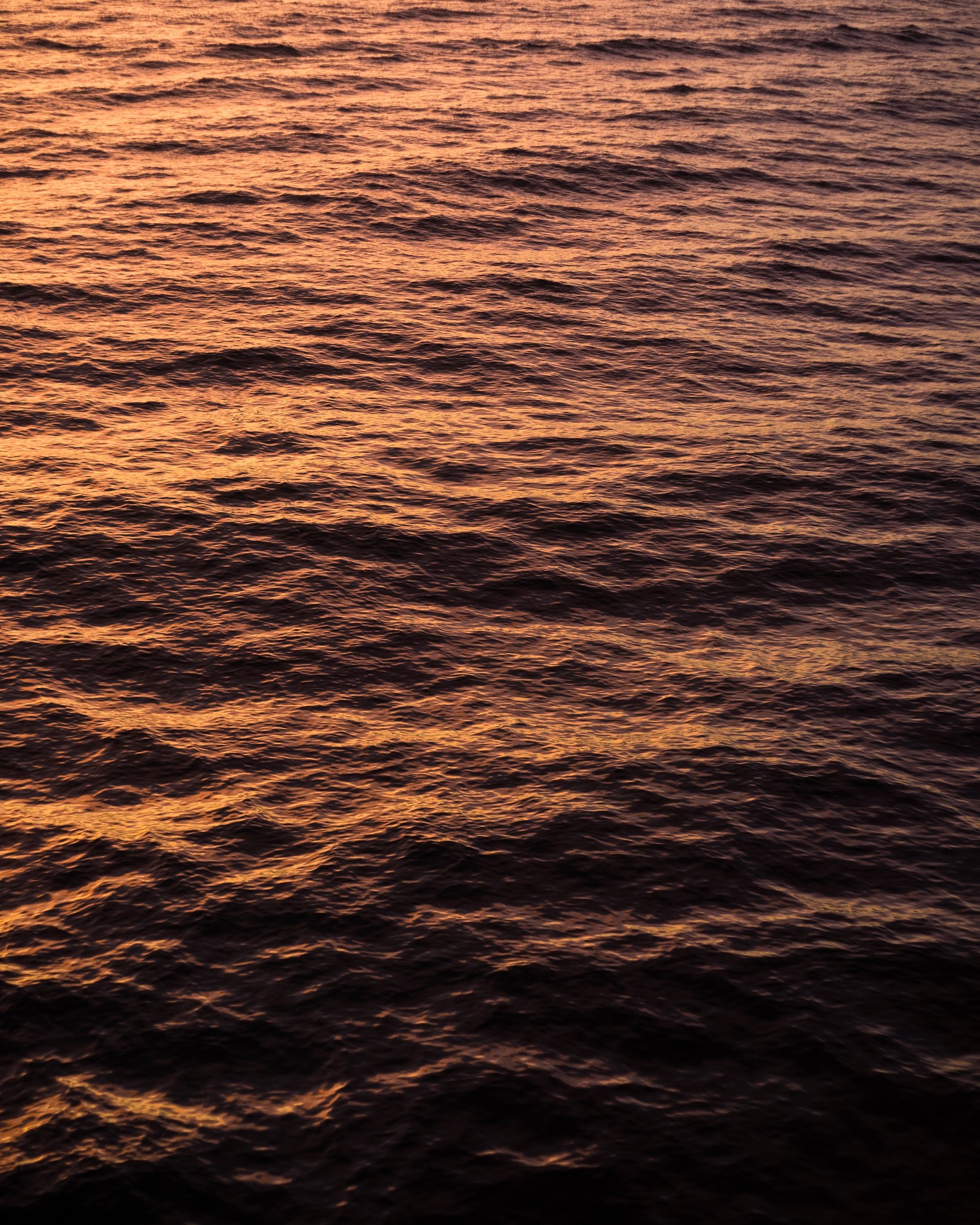 Arafed view of a body of water with a boat in the distance (water, horizon, sea, orange, calm)