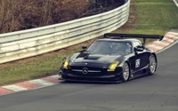 Voiture de sport Mercedes-Benz SLS AMG courant sur une piste avec un aileron arrière proéminent.