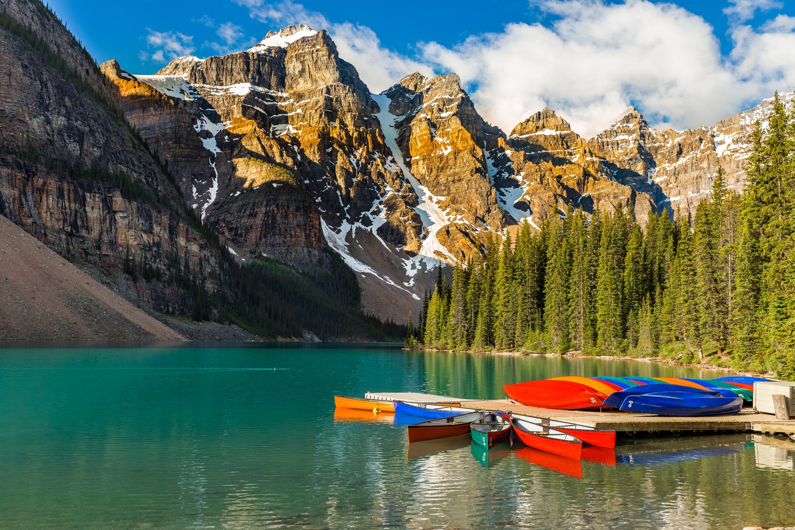 Barcos estão atracados em um cais em frente a uma montanha (lago moraine, barcos de caiaque, multicolorido, cadeia de montanhas, coberto de neve)