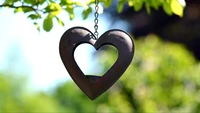 Heart-shaped pendant hanging from a branch, surrounded by lush greenery.