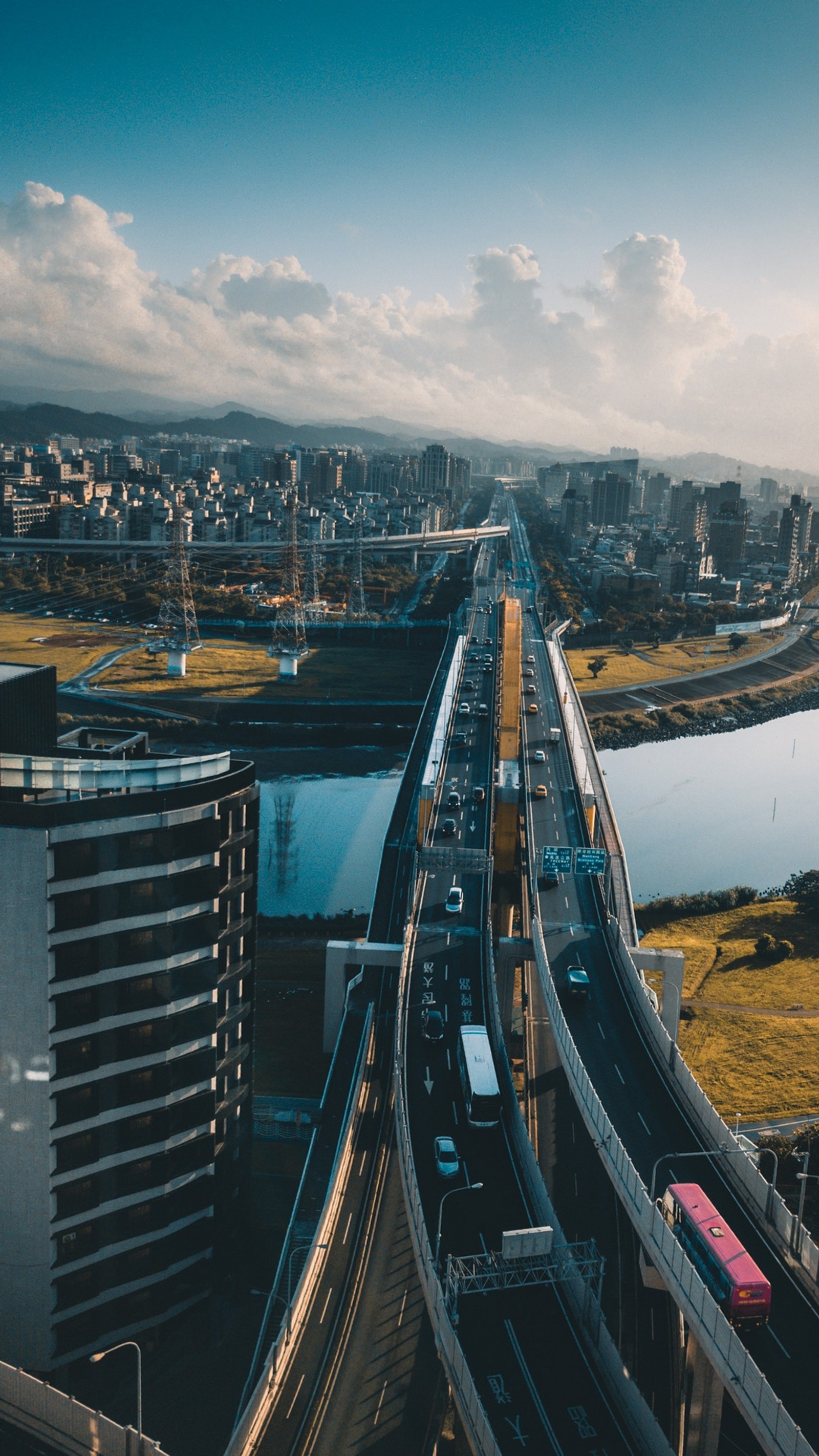 Arafed view of a highway with a bridge and a river (city, cloud, daytime, building, nature)