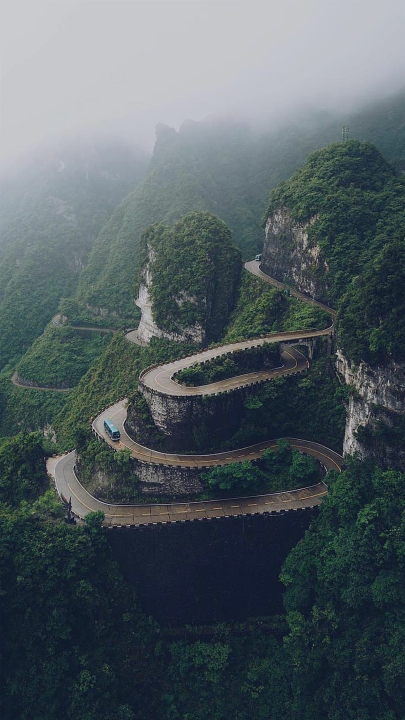 Vue aérienne d'une route sinueuse dans les montagnes avec une voiture qui y roule (paysage, montagne, nature)