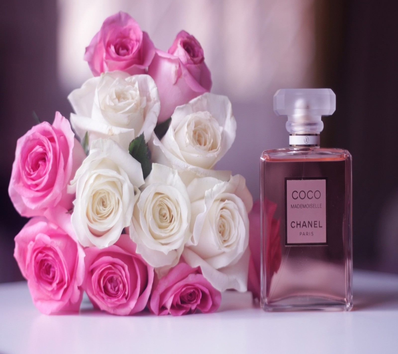 A close up of a bottle of perfume next to a bouquet of roses (lovely, nice, pink, roses)