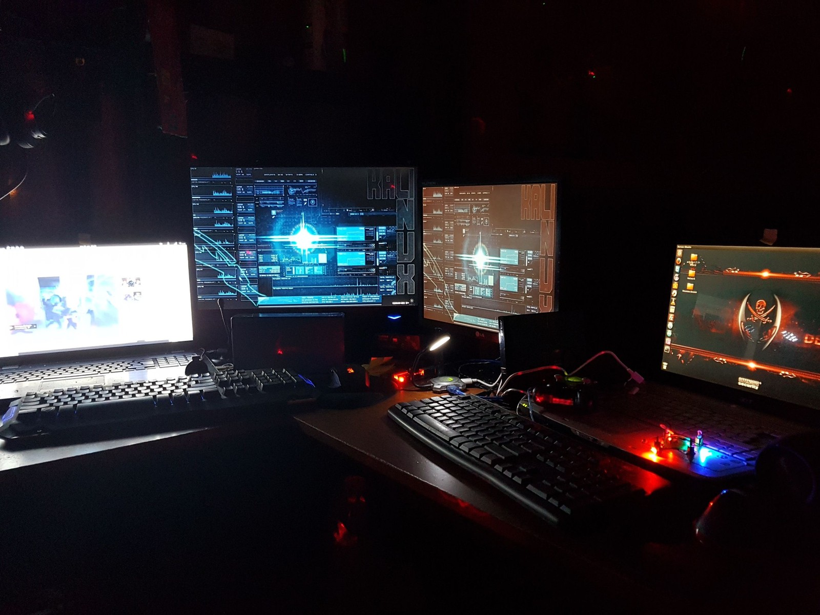 There are three computers and a laptop on a desk in the dark (hacker, technology, computer)