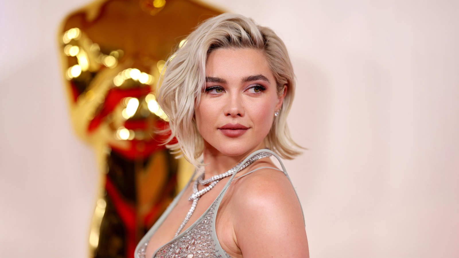 Uma dama em um vestido brilhante posando para uma foto em frente a uma estátua (florence pugh, óscar, celebridade)