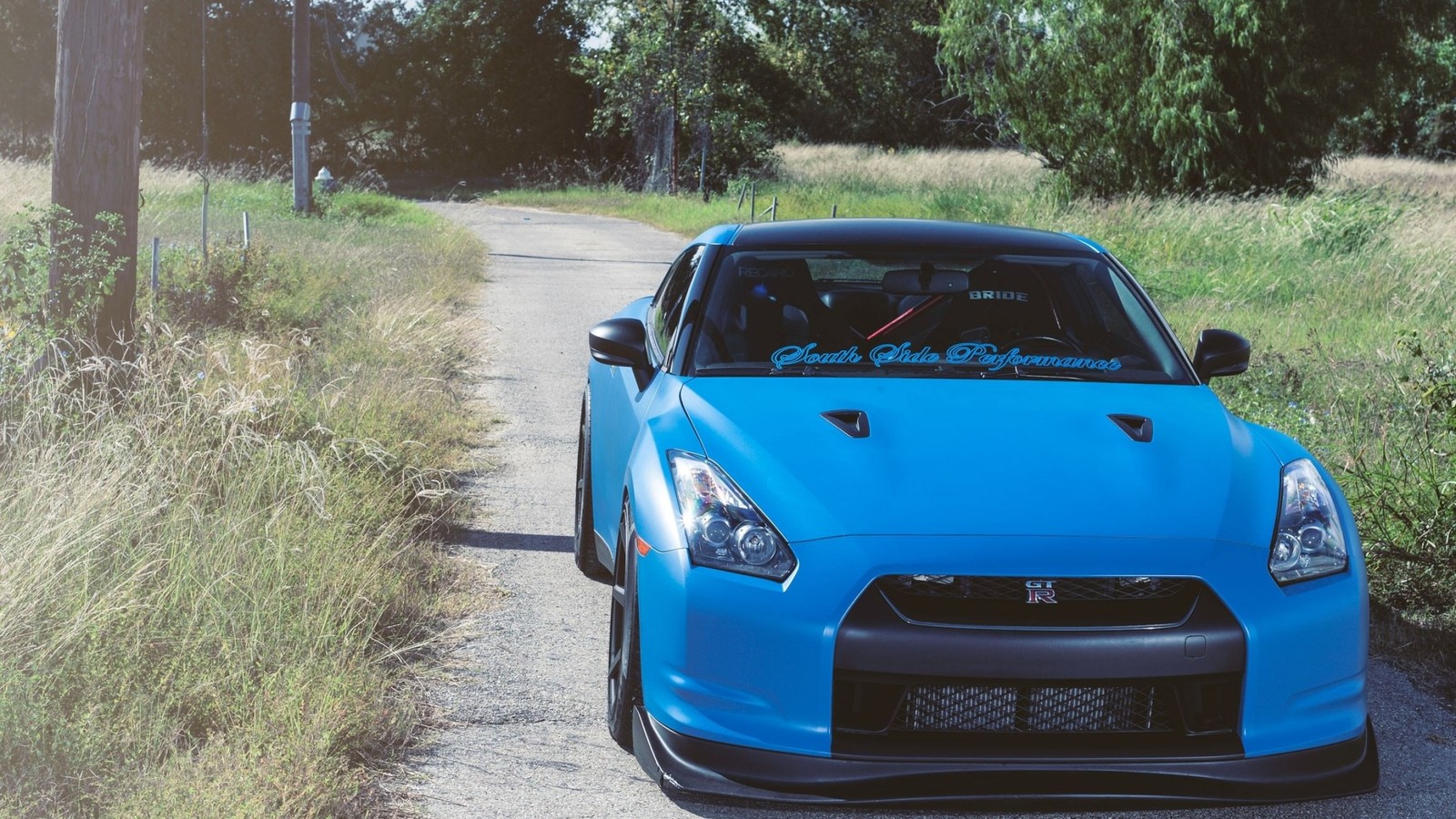 A close up of a blue sports car parked on a dirt road (nissan, sports car, car, supercar, sportscar)