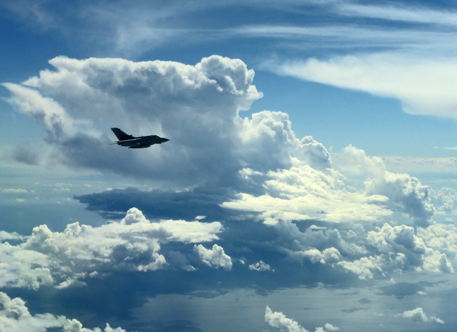 There is a jet flying through the clouds in the sky (airplane, aircraft, cloud, atmosphere, daytime)