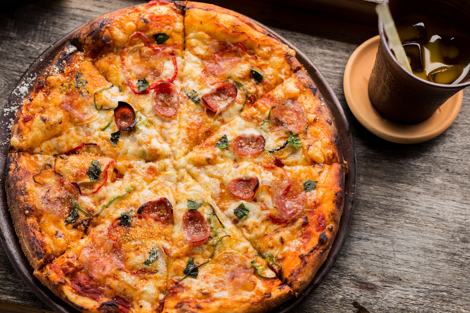 A close up of a pizza on a pan with a cup of tea (pizza, restaurant, cuisine, dish, food)