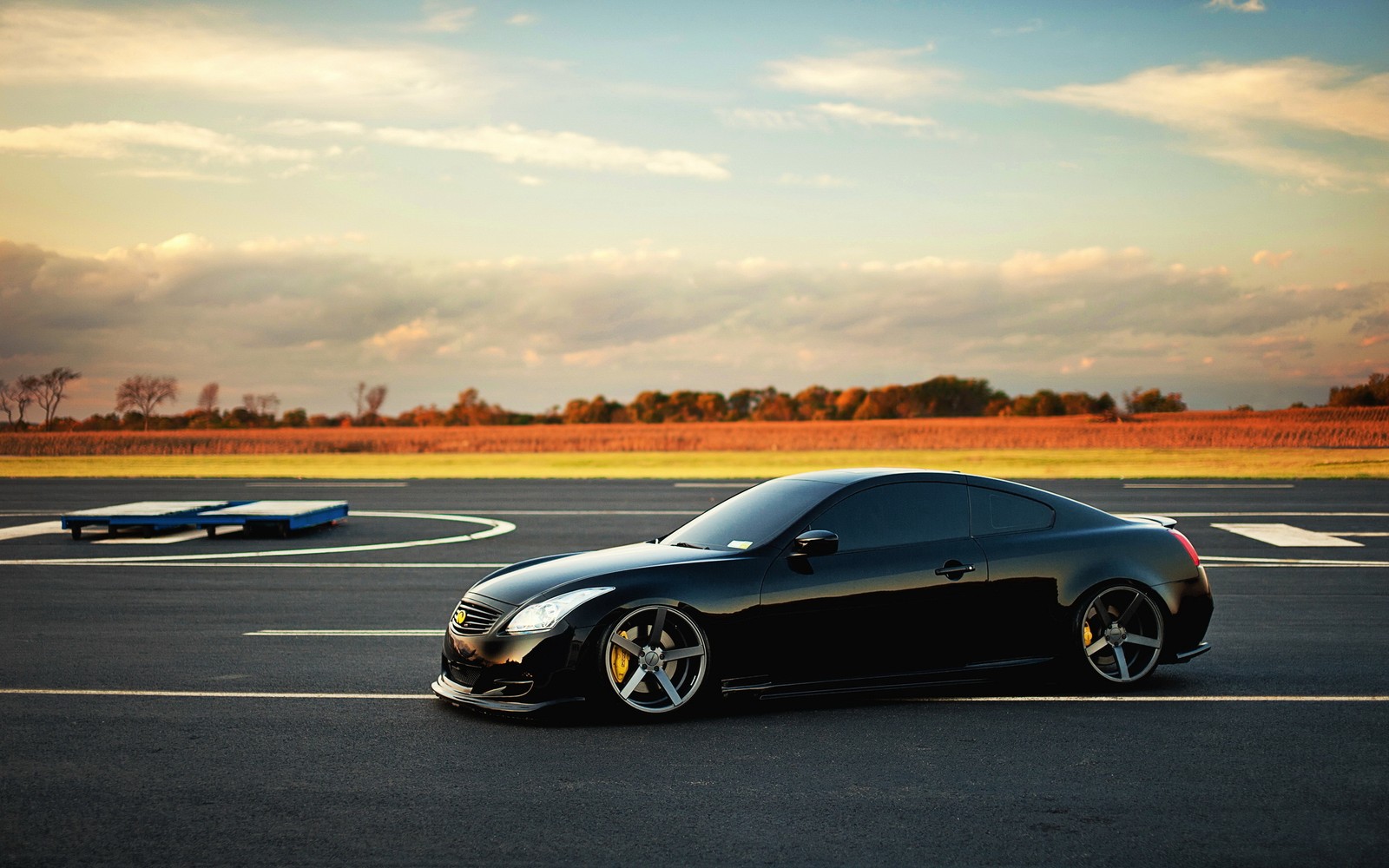 Carro esportivo preto arafed em uma pista com um pequeno avião ao fundo (infiniti, carro, carro esportivo, aro, roda)