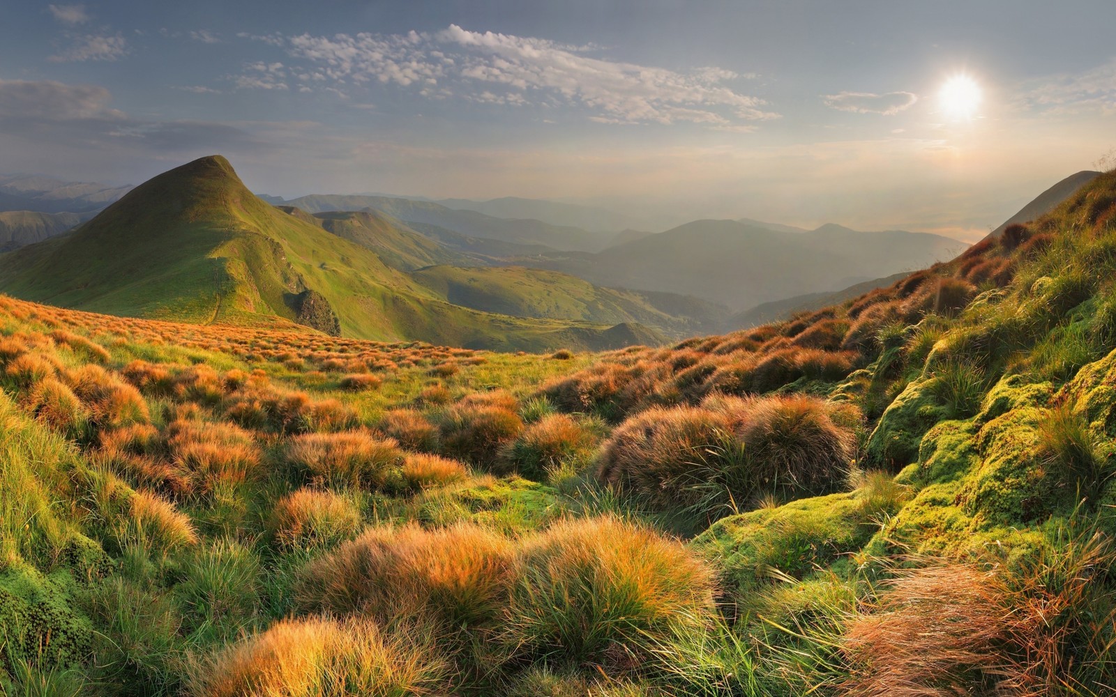 Uma vista de um campo gramado com uma montanha ao fundo (formas montanhosas, natureza, terras altas, colina, vegetação)