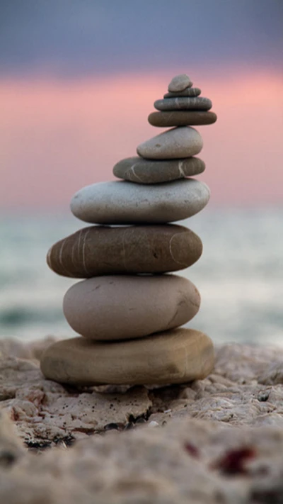 Torre de piedras equilibrada junto al mar al anochecer