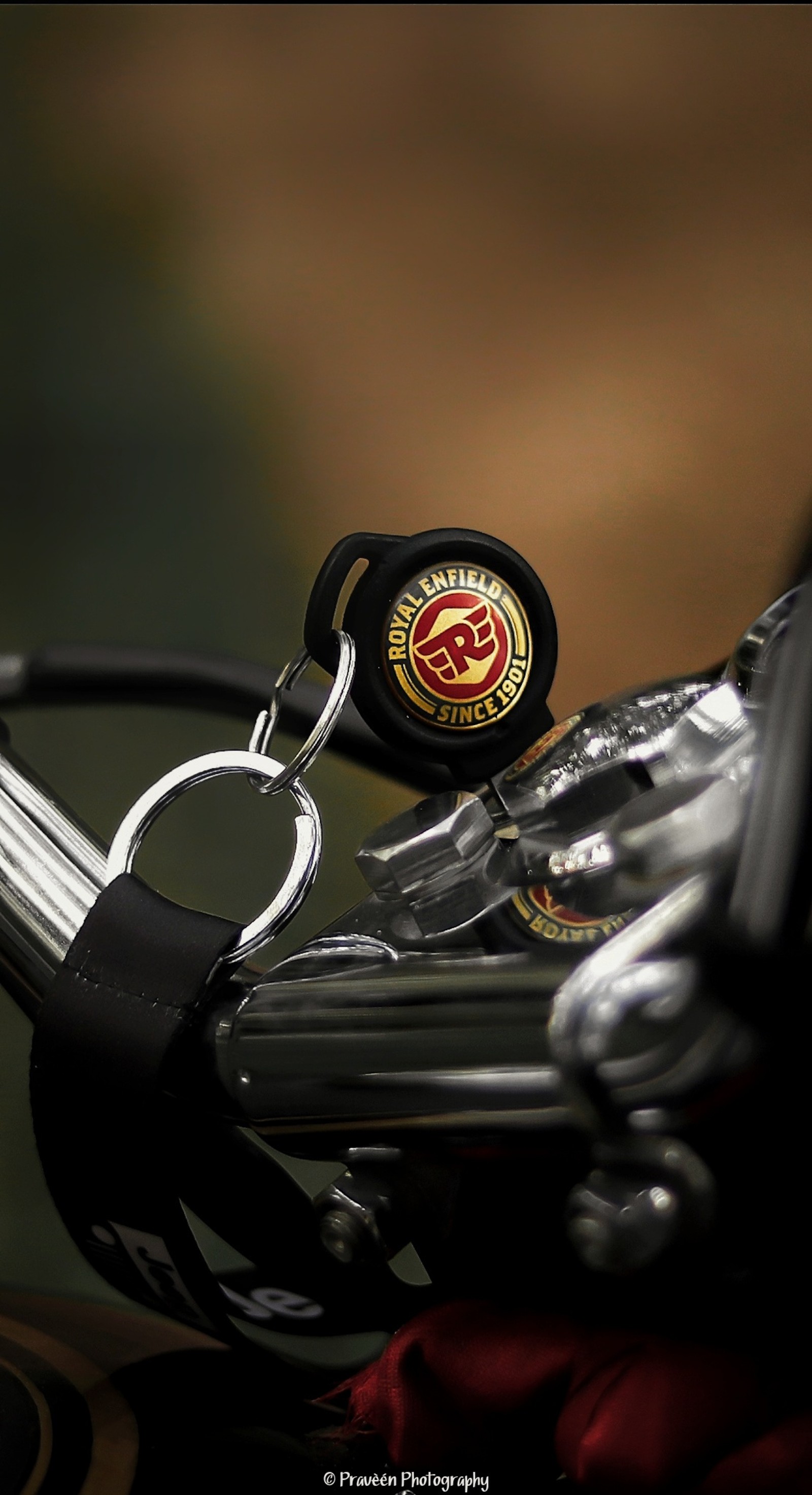 There is a close up of a motorcycle handlebar with a keychain (black, bullet, enfield, keychain, luxury)