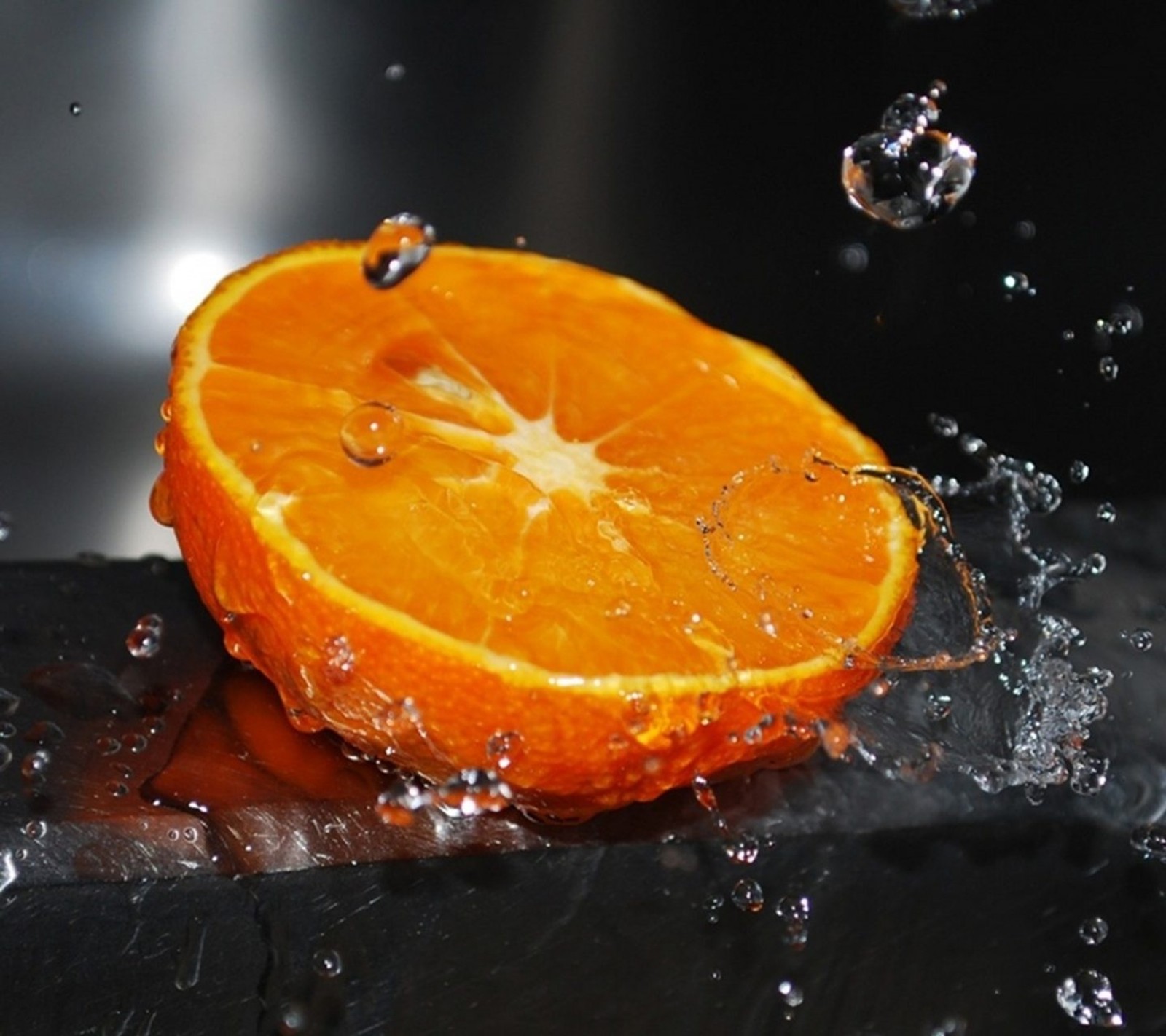 Hay una naranja que está cayendo en el agua (genial, gotas, fruta, agradable, naranja)