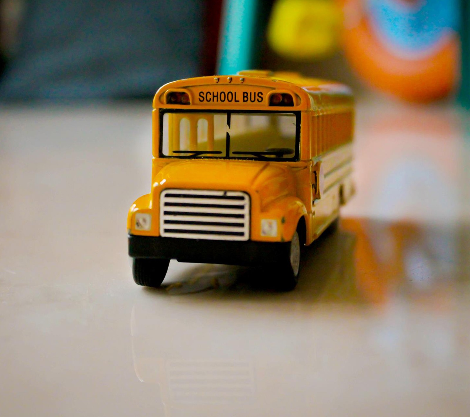 There is a toy bus that is sitting on a table (bus, child, fun, kid, nice)