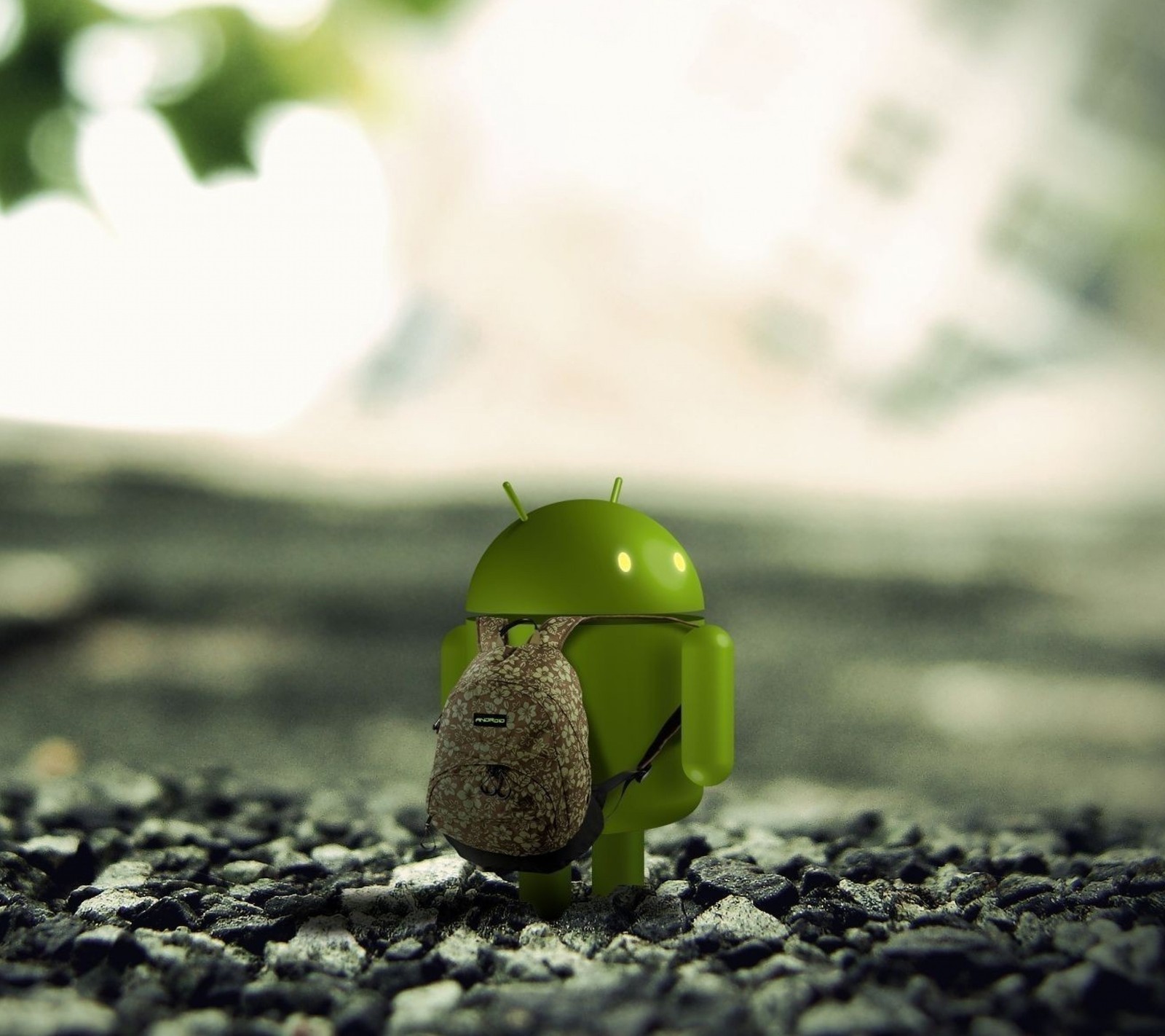 There is a small green android toy sitting on a gravel ground (android, backpack, hd, mobile, science)