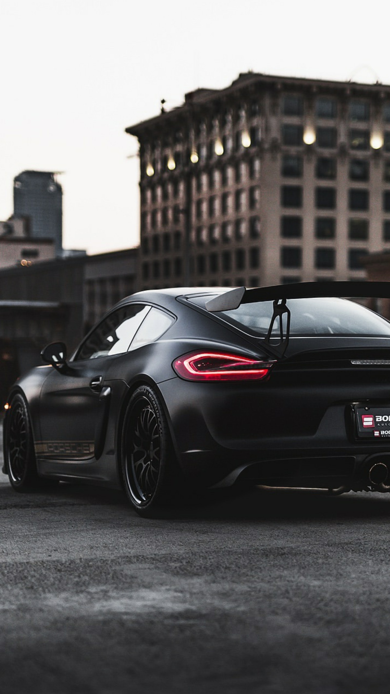 A close up of a black sports car parked in a parking lot (black, car, cayman, city, hd)