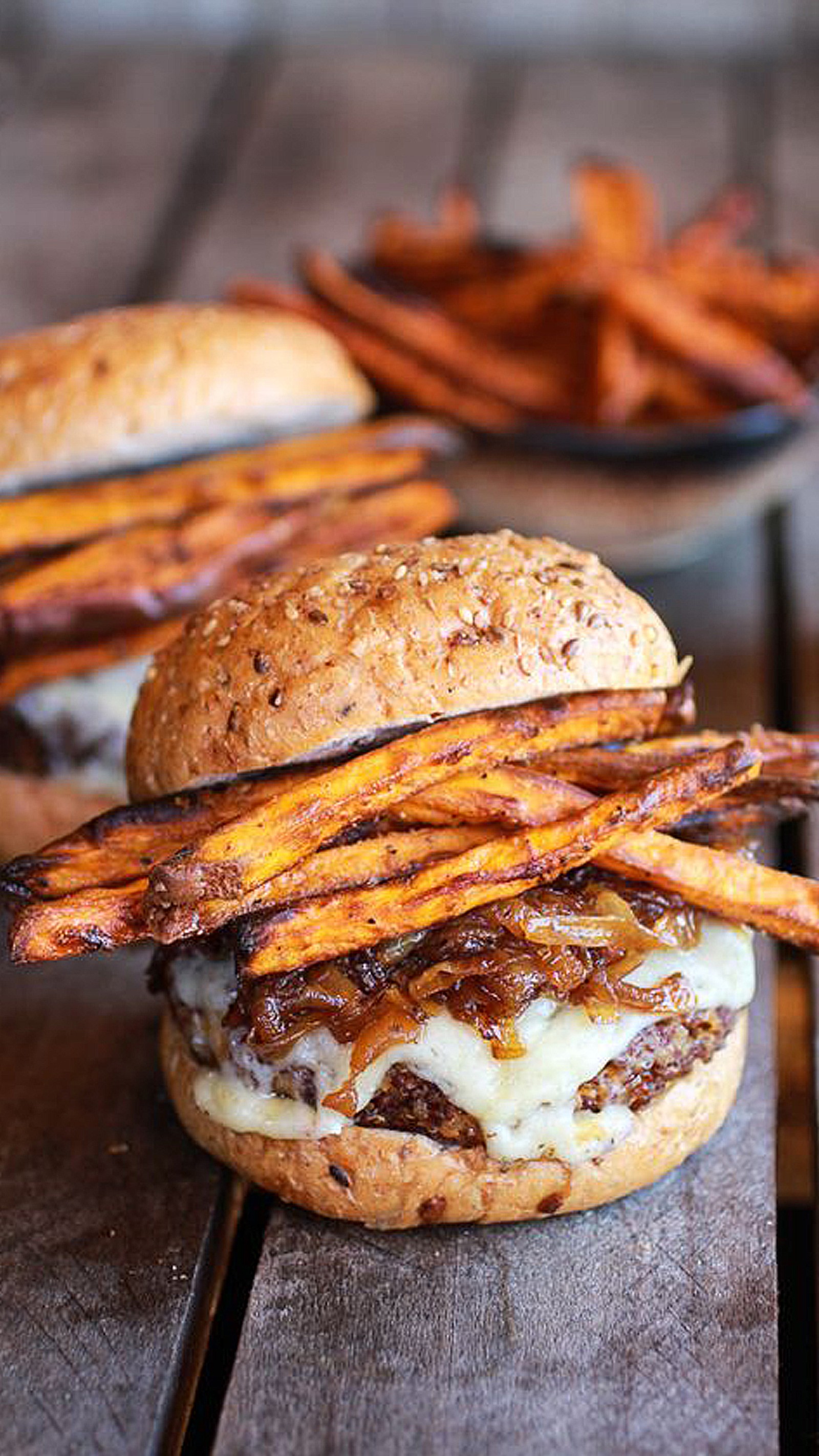 Hay dos hamburguesas con papas fritas en una mesa de madera (comida, hamburguesa)