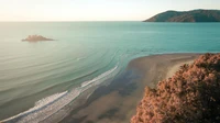 Paisagem de praia serena com ondas suaves e fundo montanhoso