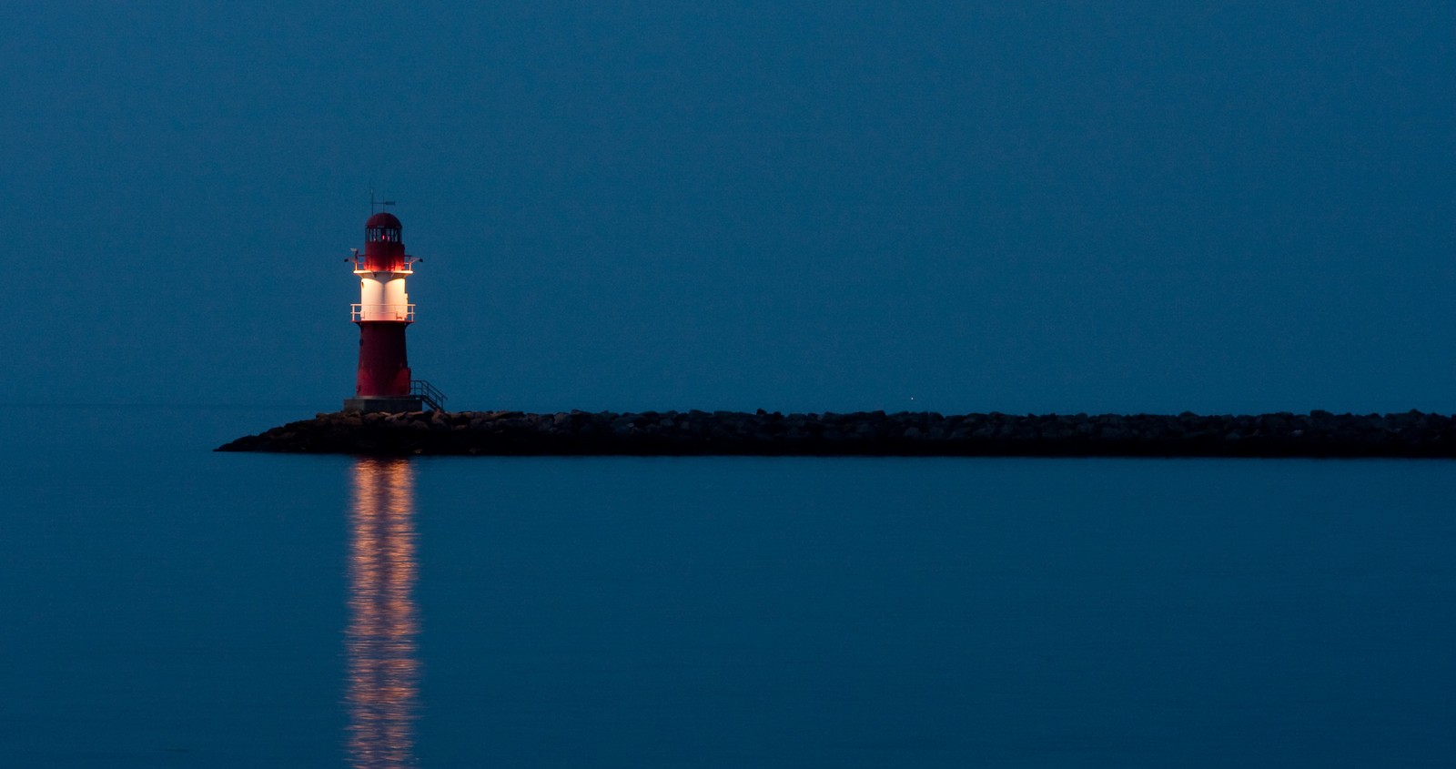 Farol no meio do oceano à noite (farol, torre, água, reflexo, calmo)