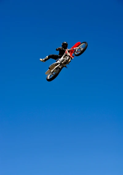 Executante de manobras de motocross freestyle pairando contra um céu azul claro