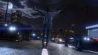 Um jogador está confiante no meio de uma rua da cidade à meia-noite, cercado por uma fila de carros elegantes, iluminados por postes de luz e pela luz da lua, capturando a essência de um momento de jogo aventureiro em Grand Theft Auto V.