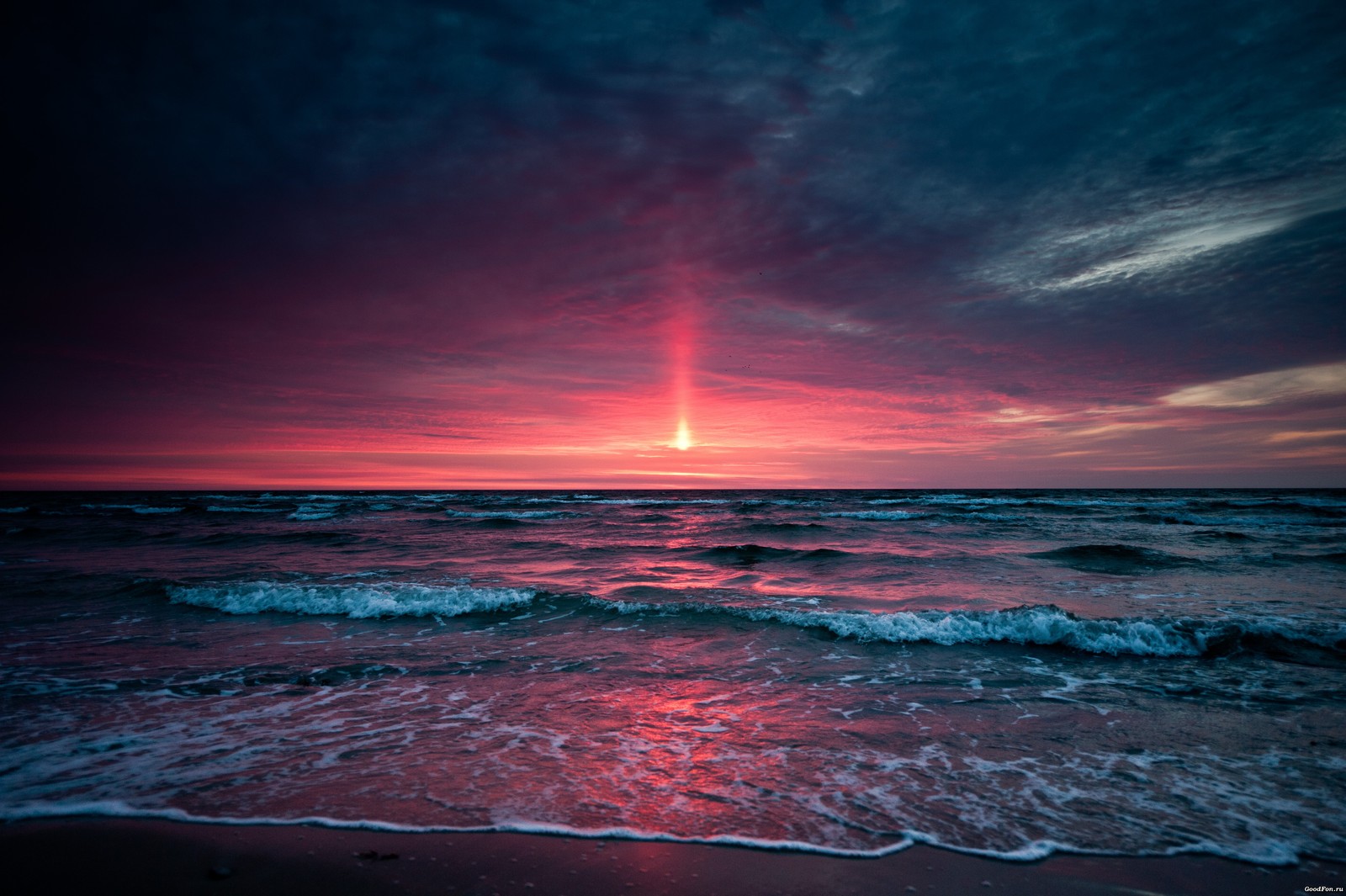 Una puesta de sol sobre el océano con una brillante luz roja brillando a través de las nubes (atardecer, horizonte, naturaleza, mar, océano)