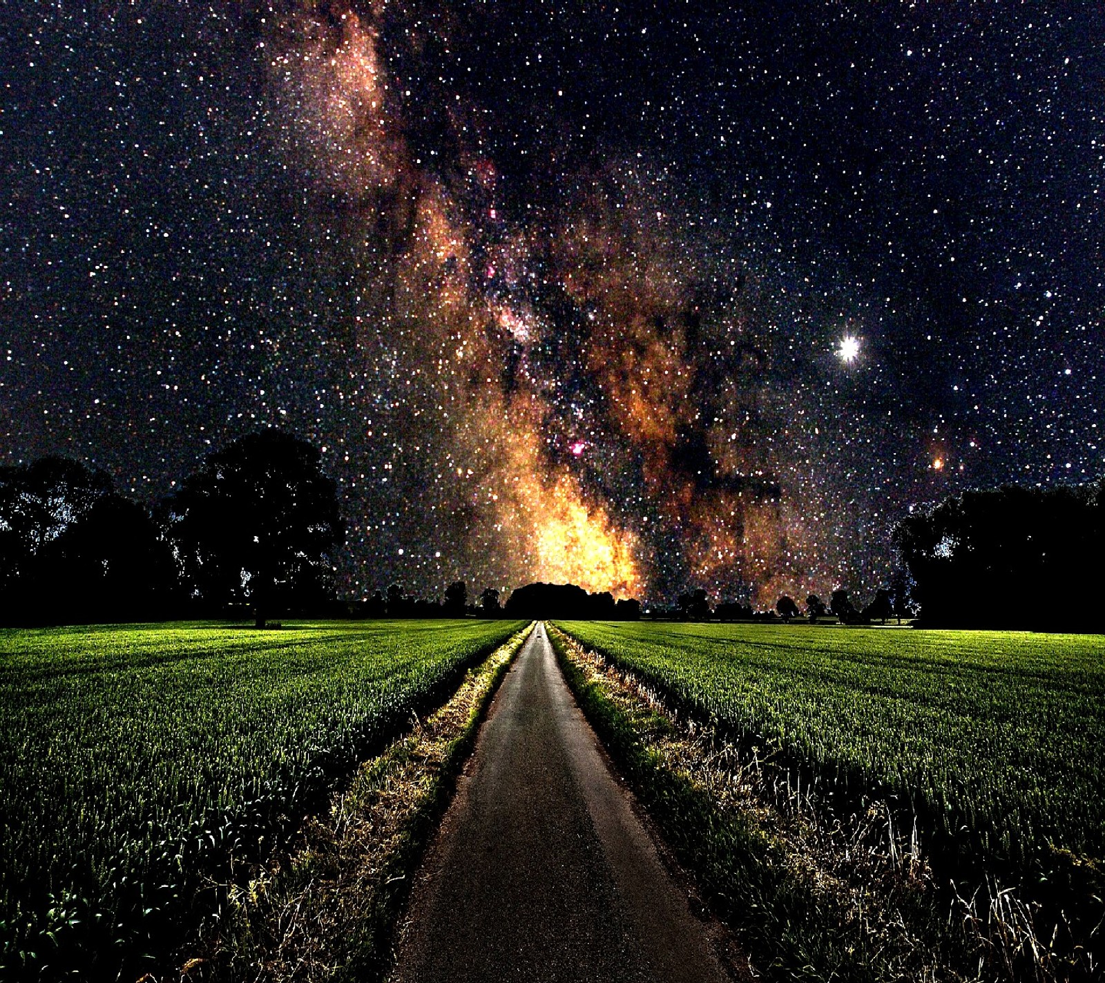 Una vista de una carretera que lleva a un campo con un cielo lleno de estrellas (tough night)