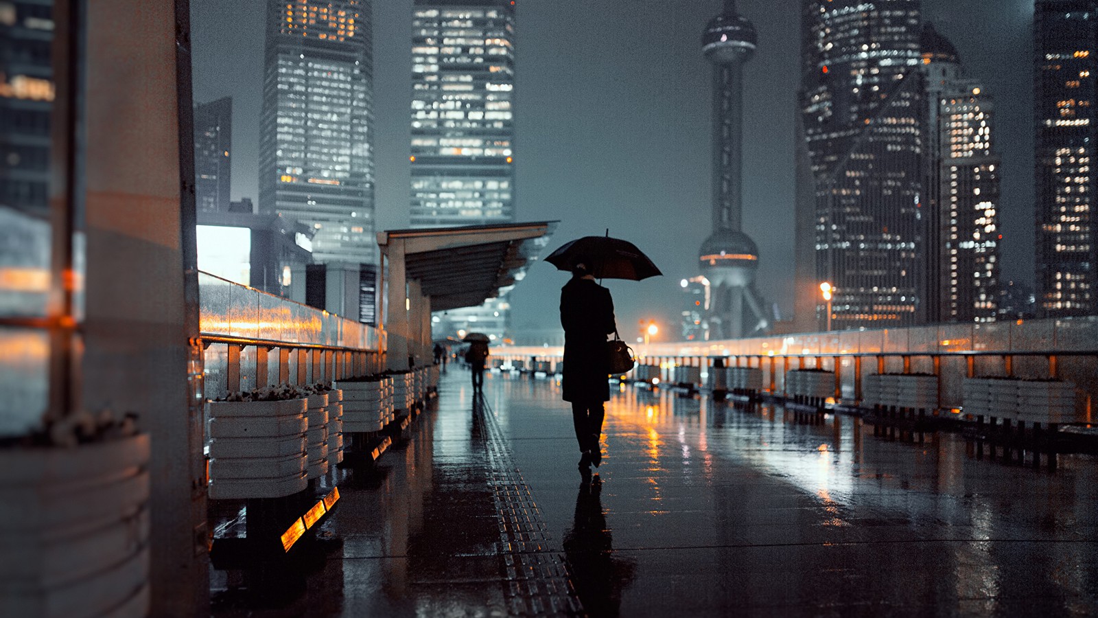 Eine person geht mit einem regenschirm auf dem bürgersteig (regen, metropole, stadtgebiet, stadt, reflexion)