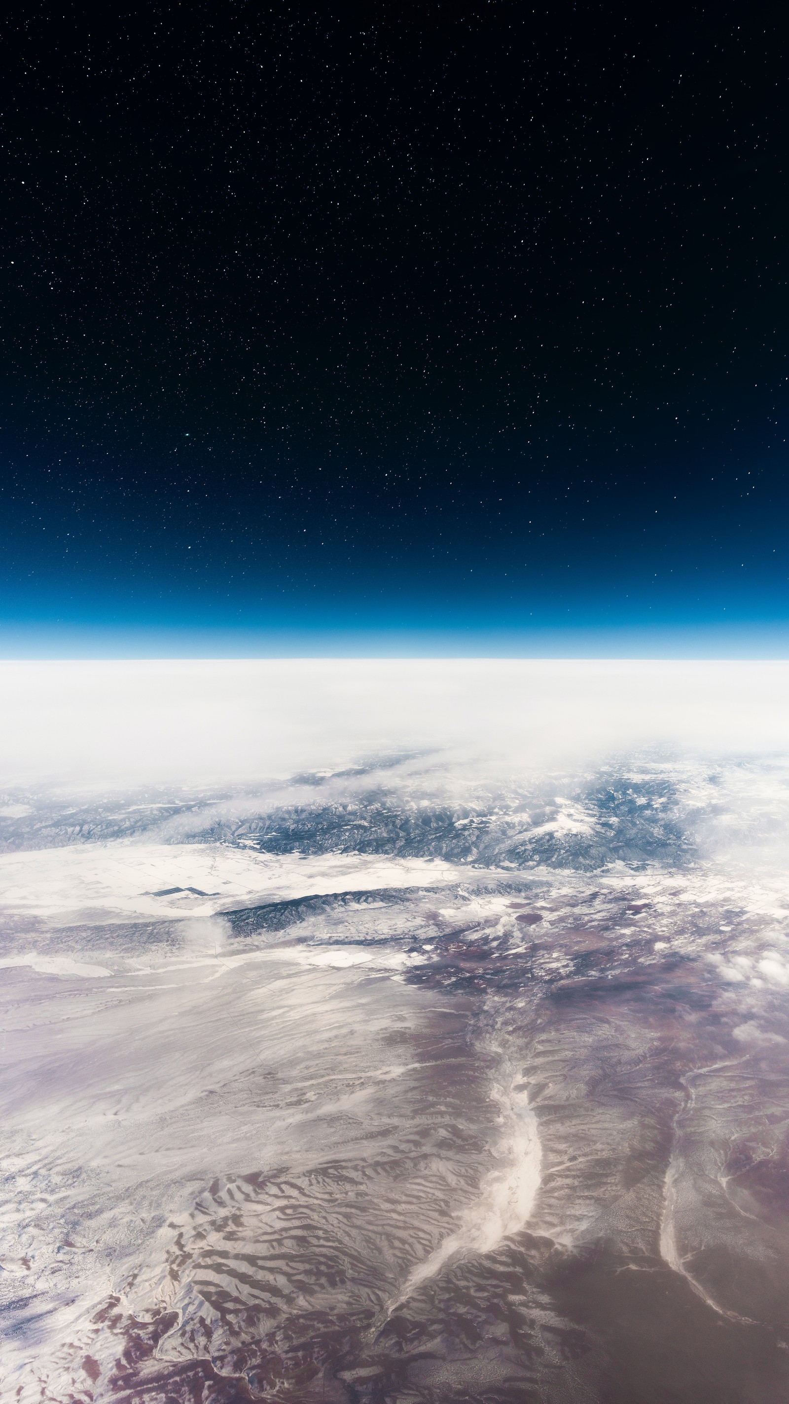 A view of the earth from space with a star filled sky (earth, horizon, above clouds, starry sky, blue sky)