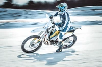 Pilote en action sur moto Husqvarna sur terrain enneigé