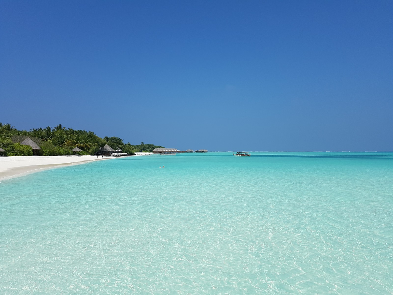 There is a beach with a boat in the water and a hut in the distance (sea, maldives, beach, atoll, vacation)