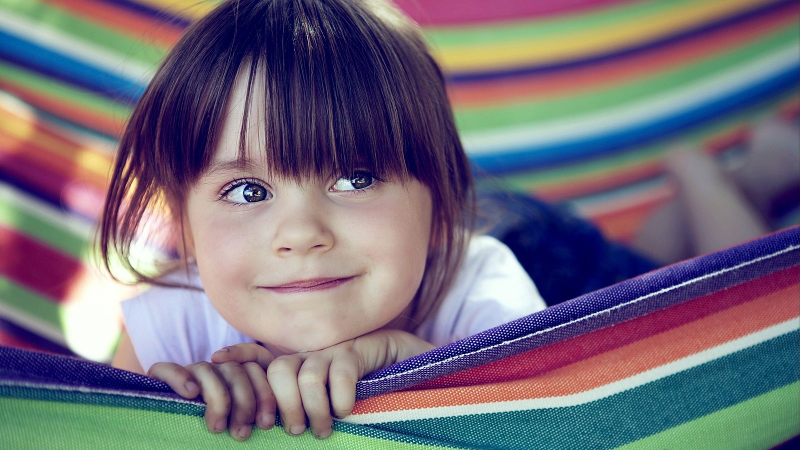 Arafed little girl laying in a hammock with her hands on her chin (child, facial expression, hairstyle, girl, beauty)