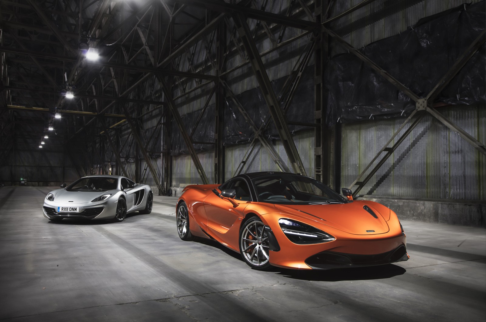 Dos coches deportivos naranjas estacionados en un gran almacén. (mclaren, coche, supercoche, coche deportivo, coche de carreras)