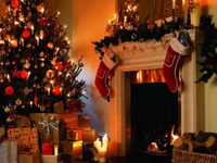 A beautifully decorated Christmas tree adorned with lights and ornaments stands beside a cozy fireplace, complete with stockings and gifts, creating a warm holiday ambiance.