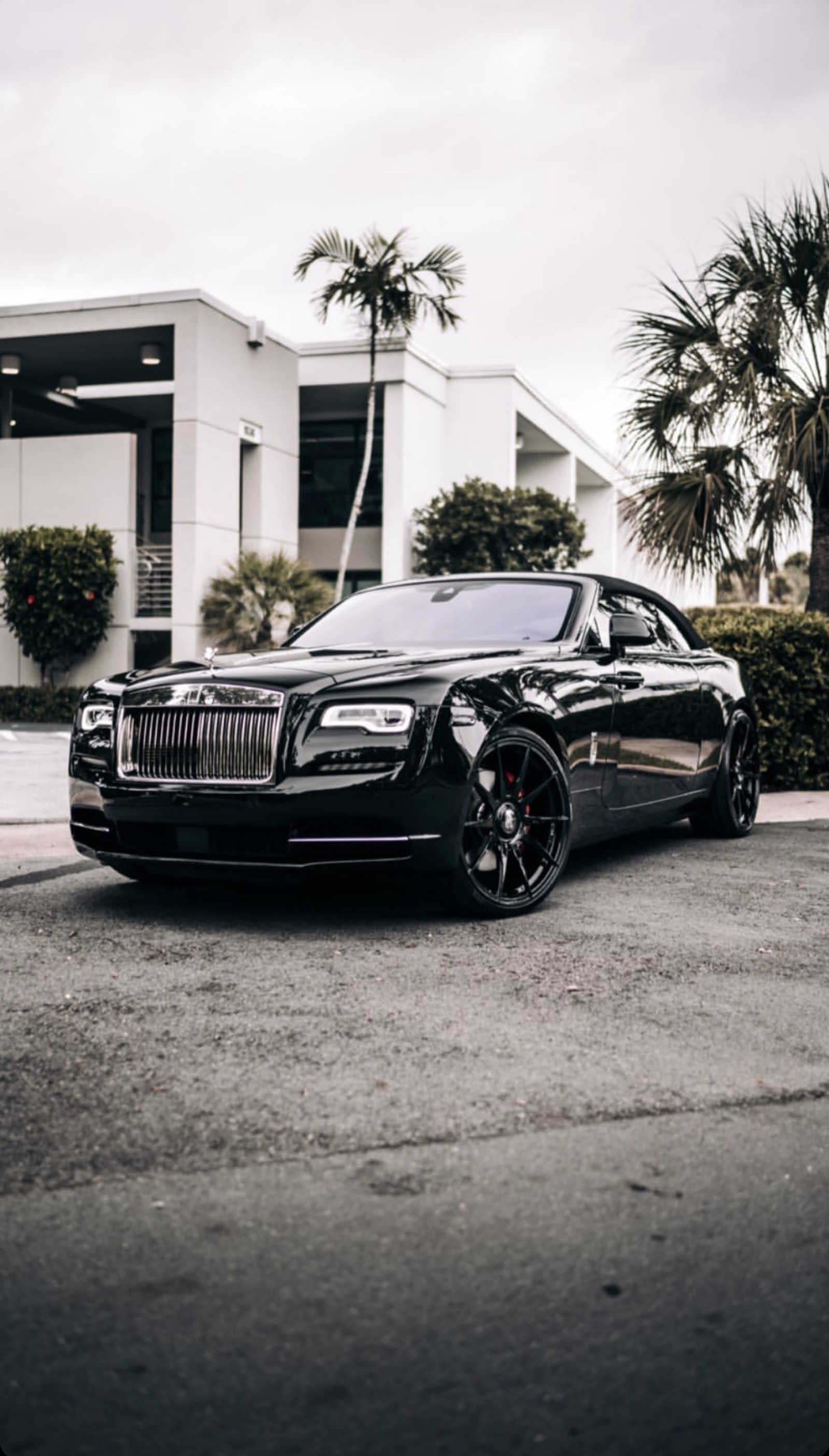 A close up of a black car parked on a street (car, sport, rolls, black)