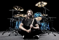 Dave Grohl, sitzt vor einem lebhaften blauen Schlagzeug, hält Drumsticks und verkörpert den Geist eines leidenschaftlichen Musikers und Schlagzeugers.