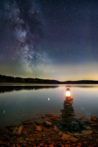 Noite serena à beira do lago: uma lanterna ilumina o reflexo da Via Láctea