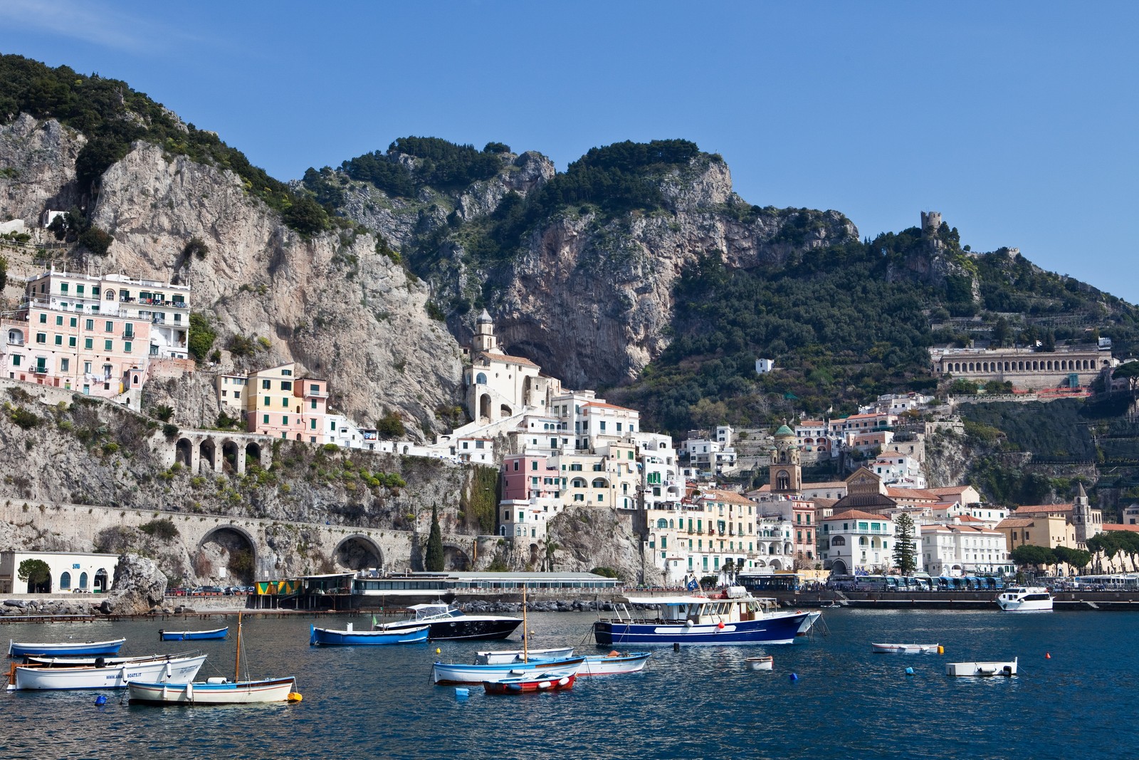 Barcos estão atracados na água perto de uma montanha e uma cidade (manarola, positano, costa, cidade, corpo de água)