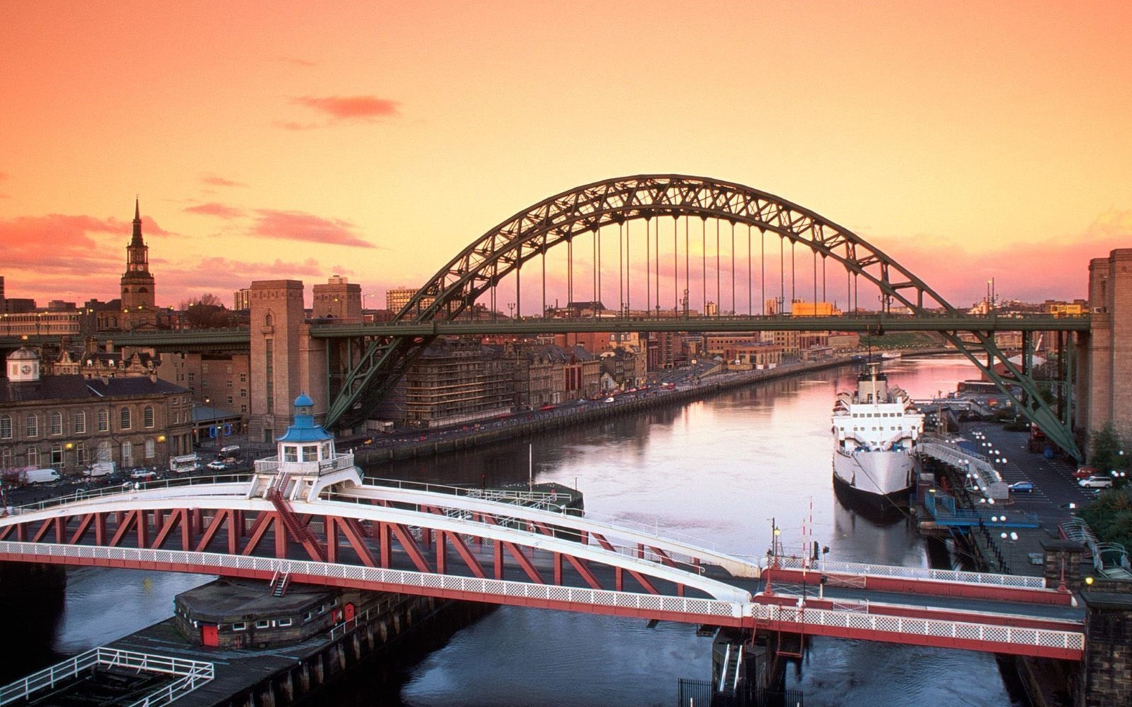 Puente árabe sobre un río con una ciudad de fondo (puente de tyne, puente del milenio de gateshead, gateshead millennium bridge, río tyne, puente de arco)