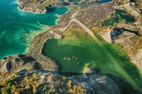 Luftaufnahme eines lebhaften Wasserlaufes, der sich durch eine raue Landschaft schlängelt, umgeben von abwechslungsreichem Terrain und buntem Laub.