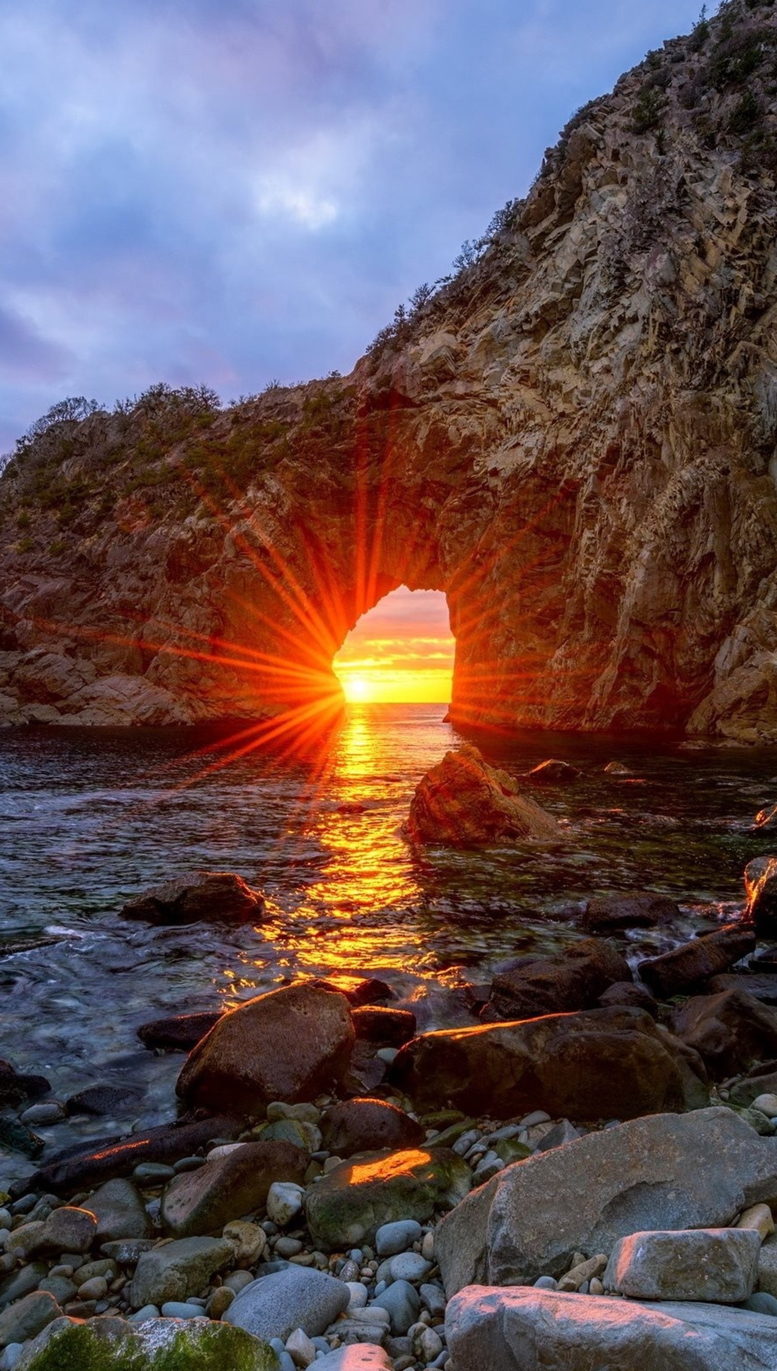 Vista de um pôr do sol sobre uma praia rochosa com um buraco no meio (2015, maçã, bonito, montanha, natureza)