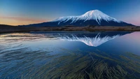 Snow-capped mountain reflecting in a serene lake at twilight, Kamchatka Peninsula, Russia.