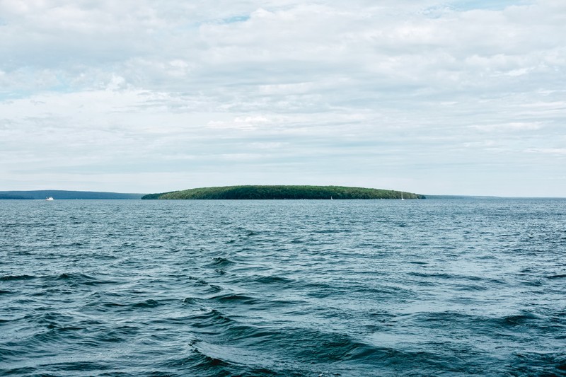 Вид на маленький остров посреди океана (водоем, море, вода, горизонт, океан)