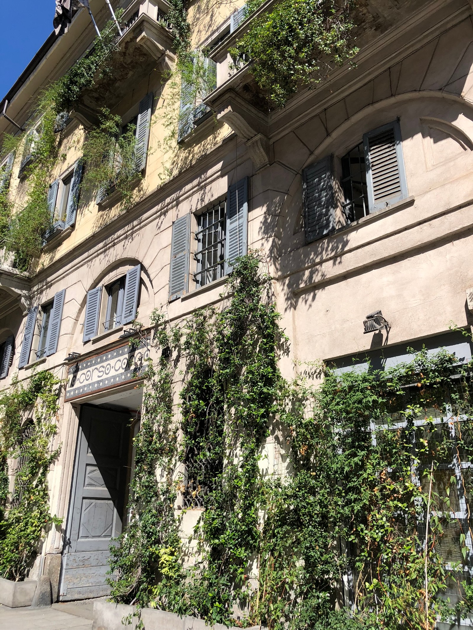 Imagem arafed de um edifício com muitas plantas crescendo em seu lado (casa, imóveis, fachada, parede, arco)