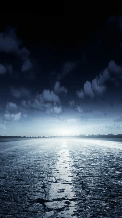 Route en asphalte éclairée par la lune sous un ciel étoilé